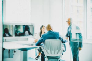 Two men shaking hands, one sitting and one standing