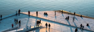 A zoomed out shot of people walking near the water
