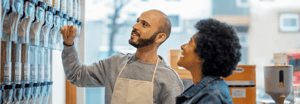 A young man wearing an apron helping a woman in a retail store